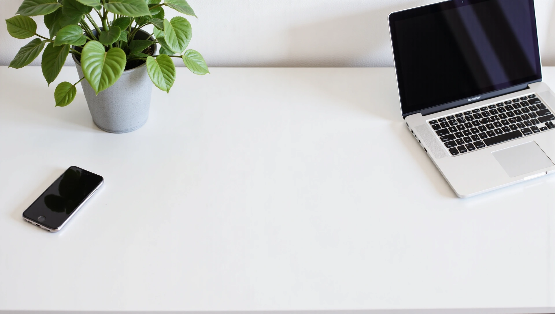 Minimalist desk with a phone, laptop, and a plant, clean and professional, no text on image