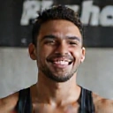 Hombre atlético sonriendo, con un fondo de gimnasio